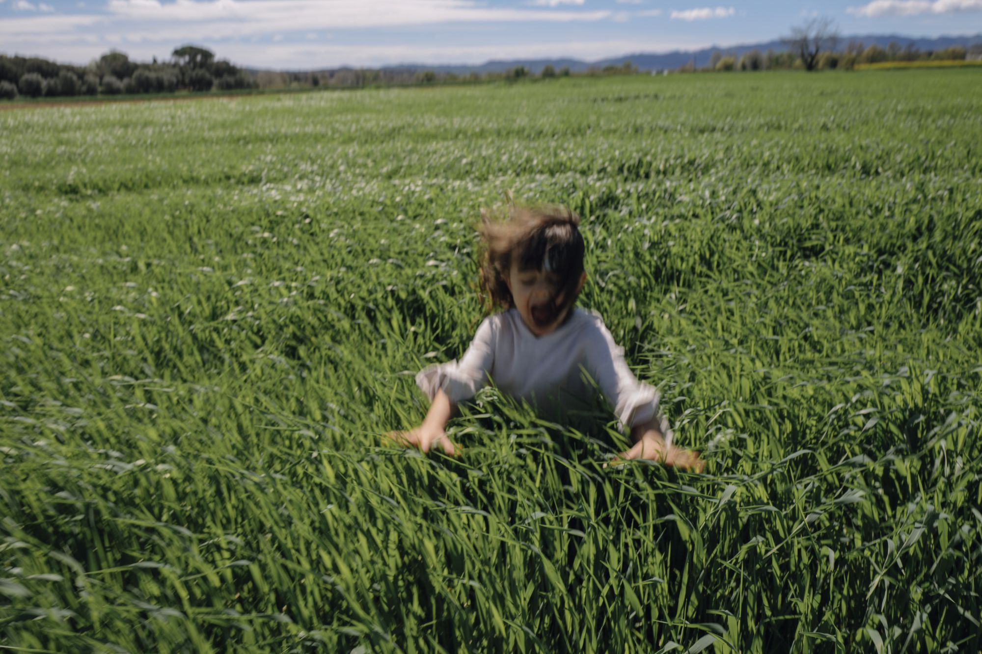 Child playing in a grassy field with dog