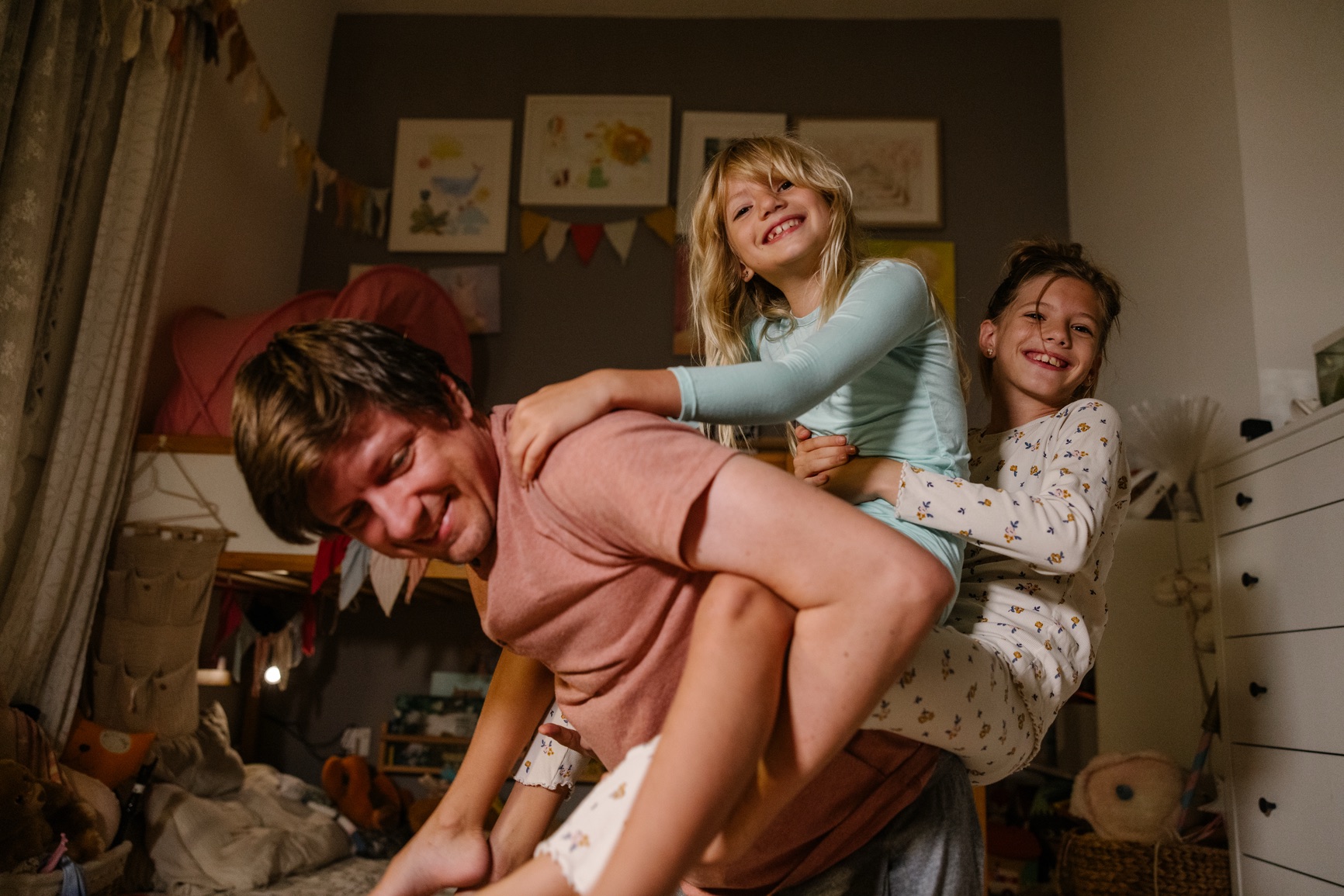 A dad playing with his two daughters at bedtime