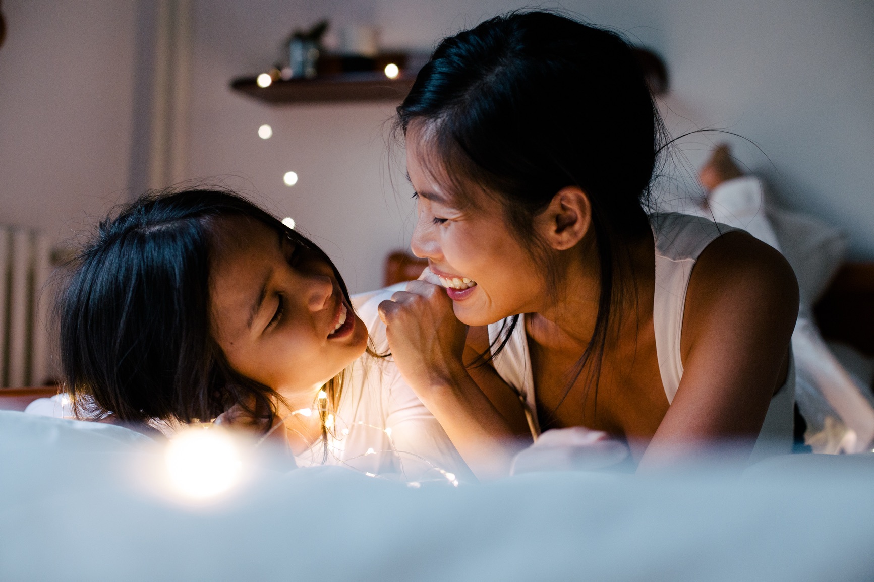 A mom and her daughter sharing a quiet moment by fairy lights